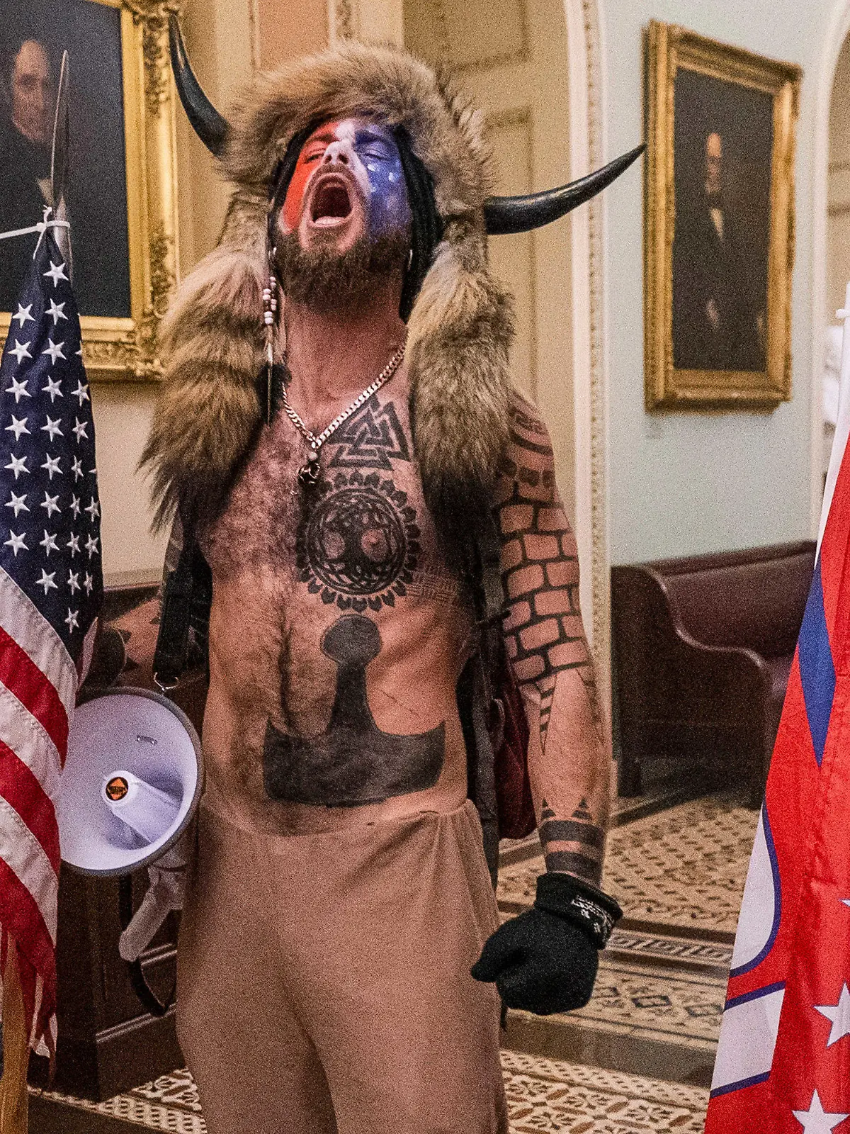 ARCHIV - 06.01.2021, USA, Washington: Unterstützer von US-Präsident Trump stehen auf dem Gang vor der Senatskammer im Kapitol. Unter den Eindringlingen in das US-Kapitol am Mittwoch in Washington sind auch Anhänger der rechten «QAnon»-Verschwörungstheorie gewesen. Vor allem Aufnahmen eines Aktivisten mit nacktem Oberkörper und einer Fellmütze mit markanten Büffelhörnern kursieren im Netz. Der «Schamane» war mit anderen bis in den Sitzungssaal des Senats vorgedrungen. Der Mann heißt Jacob Anthony Chansley und ist auch als Jake Angeli bekannt. Er ist als Verschwörungstheoretiker in Erscheinung getreten. (zu dpa «Bericht: Sicherheitsbehörden hatten Hinweise vor Kapitol-Angriff») Foto: Manuel Balce Ceneta/AP/dpa +++ dpa-Bildfunk +++