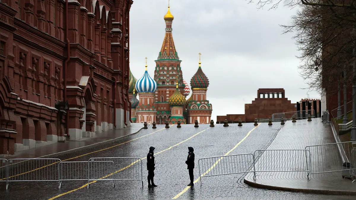 14.04.2020, Russland, Moskau: Zwei Polizisten mit Mundschutz bewachen bei Regen einen gesperrten Zugang auf dem leeren Roten Platz zur Einhaltung der Vorschriften zur Eindämmung des Coronavirus. Foto: Alexander Zemlianichenko/AP/dpa +++ dpa-Bildfunk +++