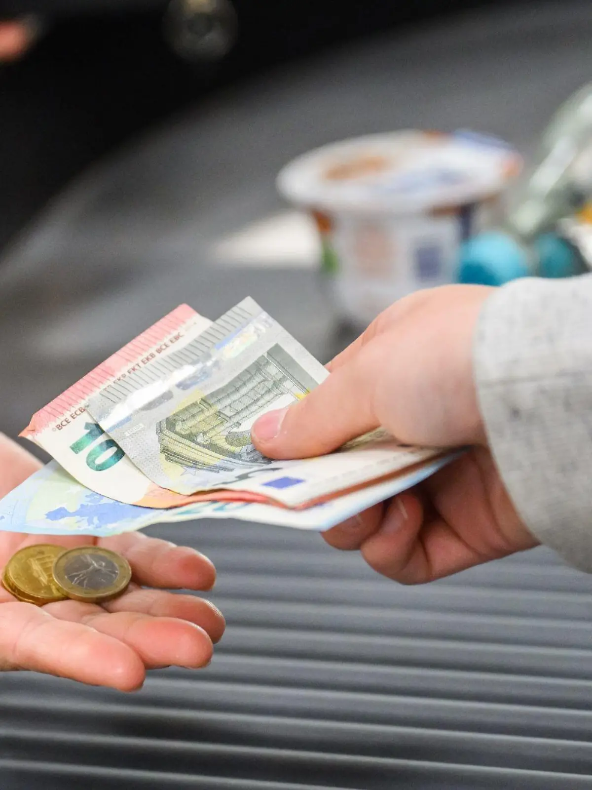 Eine Kassiererin reicht einer Kundin Wechselgeld an der Kasse eines Supermarkts.