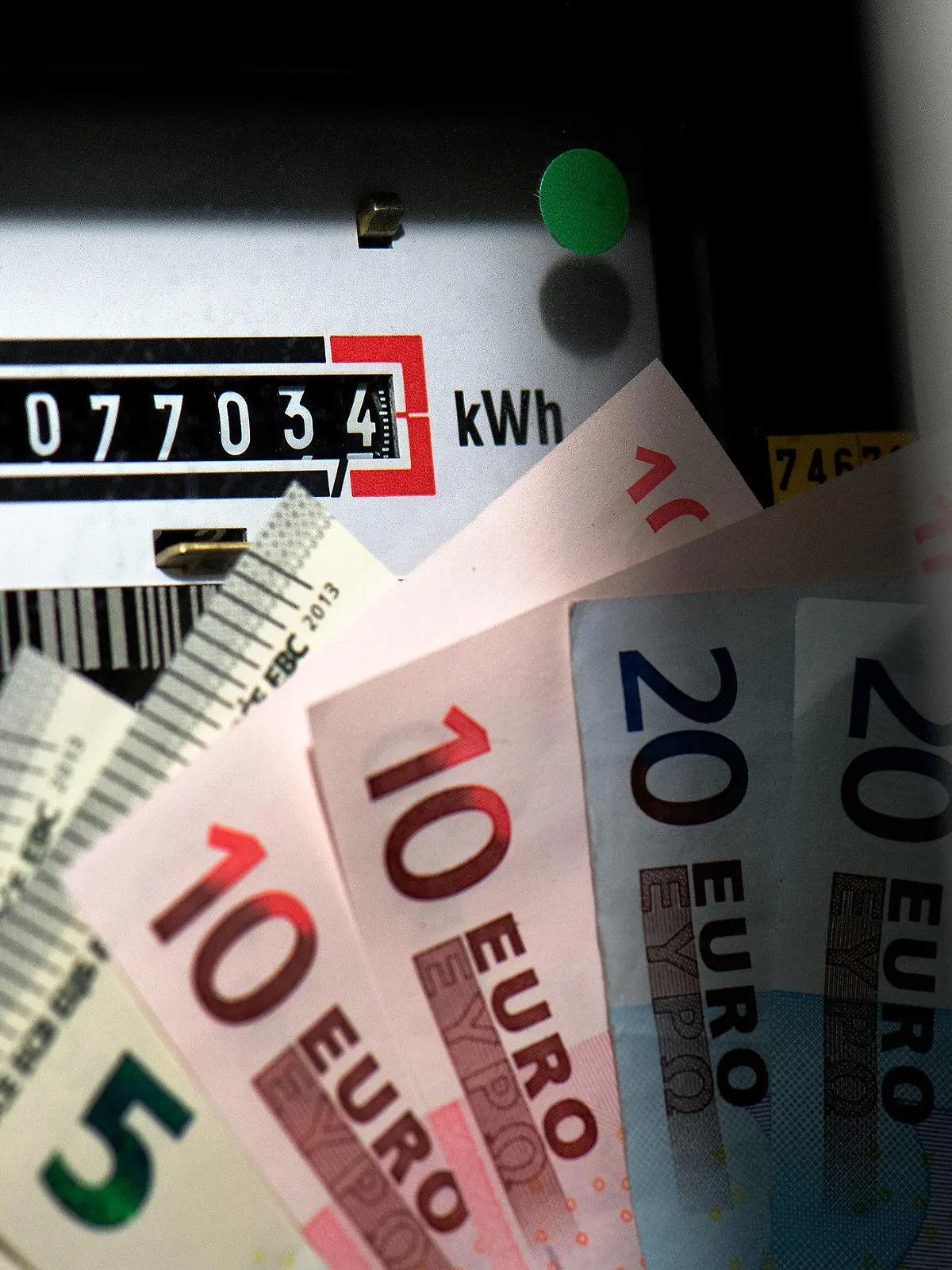 ILLUSTRATION - Vor einem Wechselstromzähler in einem Stromkasten eines Haushaltes in Dresden (Sachsen) sind am 15.10.2013 mehrere Euro Geldscheine zu sehen. Die Verbraucher in Deutschland müssen sich auf spürbare Strompreiserhöhungen einstellen. Die über den Strompreis zu zahlende Umlage zur Förderung erneuerbarer Energien werde für 2014 auf den Rekordwert von 6,240 Cent je Kilowattstunde festgesetzt, teilte der für die Verwaltung der Förderzahlungen mitzuständige Übertragungsnetzbetreiber TransnetBW mit. Foto: Arno Burgi/dpa +++(c) dpa - Bildfunk+++