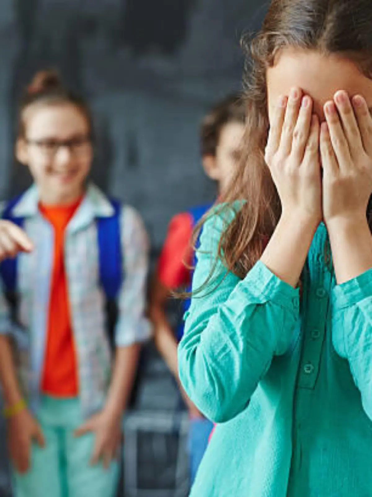 Schoolgirl crying on background of classmates teasing her