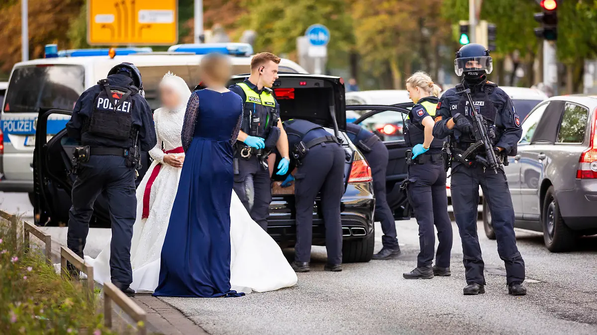 01.10.2023, Niedersachsen, Hannover: Polizisten kontrollieren Teilnehmer eines Hochzeitskorsos und ihre Fahrzeuge. Passanten wollen am Sonntagabend Schüsse aus den Autos gehört haben und wählten die 110. Acht Autos seien durchsucht worden, letztlich sei aber nichts gefunden worden. Die Hochzeitsgäste mussten ihre Limousinen verlassen - auch die Braut musste auf einer achtspurigen Hauptverkehrsstraße mitten in der City in ihrem opulenten weißen Kleid auf das Ende der Polizeidurchsuchungen warten. Foto: Moritz Frankenberg/dpa - ACHTUNG: Person(en) wurden aus persönlichkeitsrechtlichen Gründen gepixelt +++ dpa-Bildfunk +++