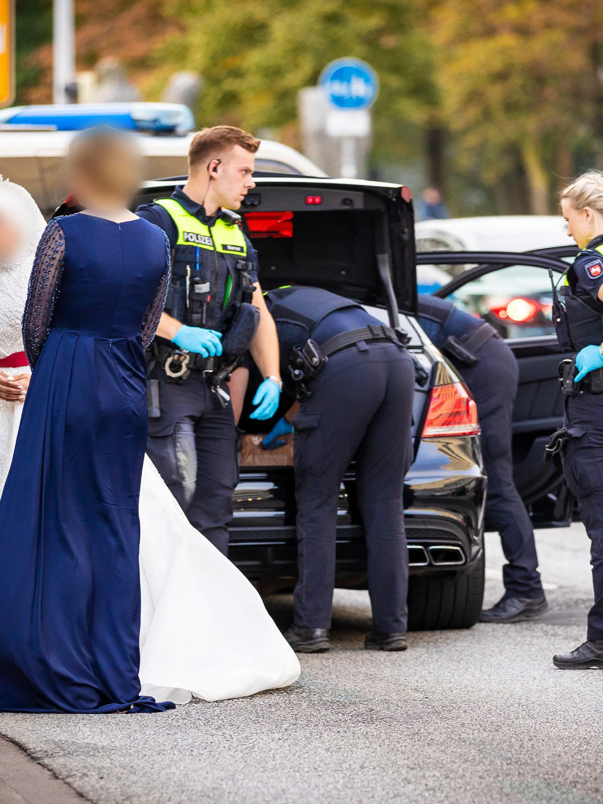 01.10.2023, Niedersachsen, Hannover: Polizisten kontrollieren Teilnehmer eines Hochzeitskorsos und ihre Fahrzeuge. Passanten wollen am Sonntagabend Schüsse aus den Autos gehört haben und wählten die 110. Acht Autos seien durchsucht worden, letztlich sei aber nichts gefunden worden. Die Hochzeitsgäste mussten ihre Limousinen verlassen - auch die Braut musste auf einer achtspurigen Hauptverkehrsstraße mitten in der City in ihrem opulenten weißen Kleid auf das Ende der Polizeidurchsuchungen warten. Foto: Moritz Frankenberg/dpa - ACHTUNG: Person(en) wurden aus persönlichkeitsrechtlichen Gründen gepixelt +++ dpa-Bildfunk +++