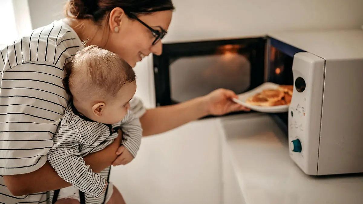 Mother preparing food with baby in arms