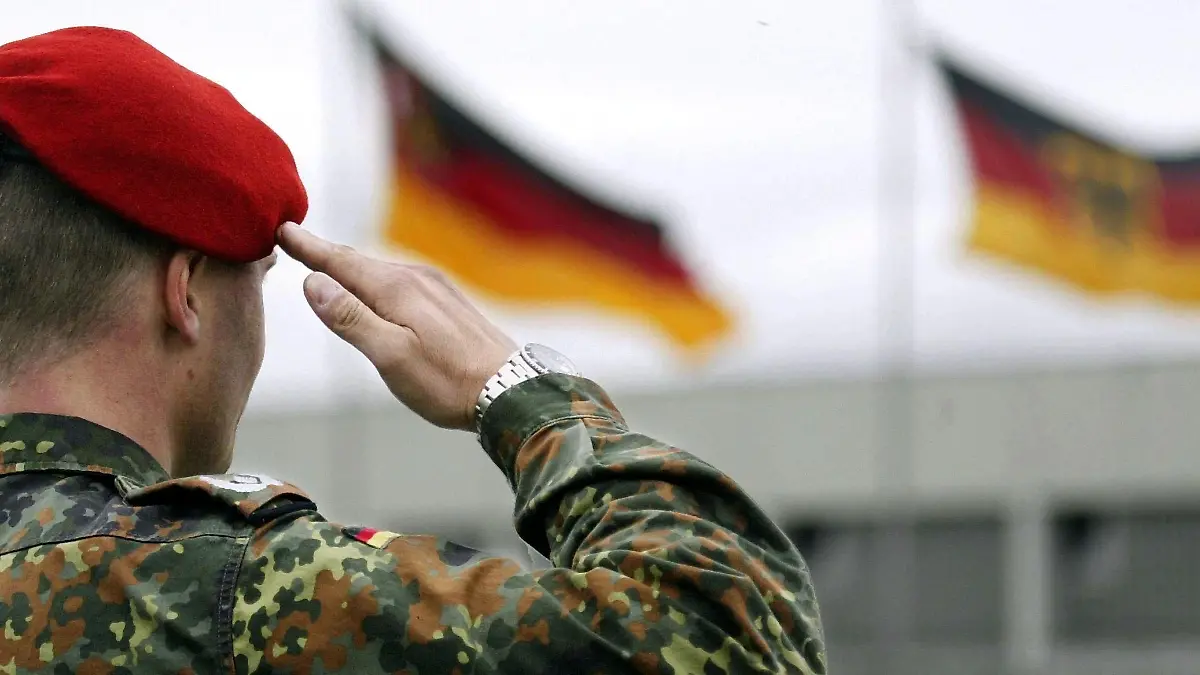 Ein Soldat der Bundeswehr salutiert, während vor ihm die deutsche Fahne weht (aufgenommen am 23.4.2004 in Speyer). Verteidigungsminister Struck (SPD) will gegen das Kölner Gerichtsurteil zur Einberufungspraxis der Bundeswehr Rechtsmittel einlegen. "Ich bin nach wie vor der Überzeugung, dass unser Rechtsstandpunkt sich vor dem Bundesverwaltungsgericht durchsetzen wird", sagte Struck am 23. April 2004. Das Verwaltungsgericht hatte entschieden, dass die derzeitige Einberufungsregelung gegen das Willkürverbot des Grundgesetzes verstößt. Er empfinde die jetzige Situation bei der Einberufung "nicht als ungerecht", so Struck. Von den Männern eines Jahrgangs blieben für den Wehrdienst nur etwa 35 Prozent übrig, weil der Rest verweigere oder aus gesundheitlichen Gründen nicht eingezogen werden könne. Zur Regelung, dass keine Verheirateten und keine Männer über 23 Jahren mehr eingezogen werden, sei ein Gesetzentwurf in Arbeit.