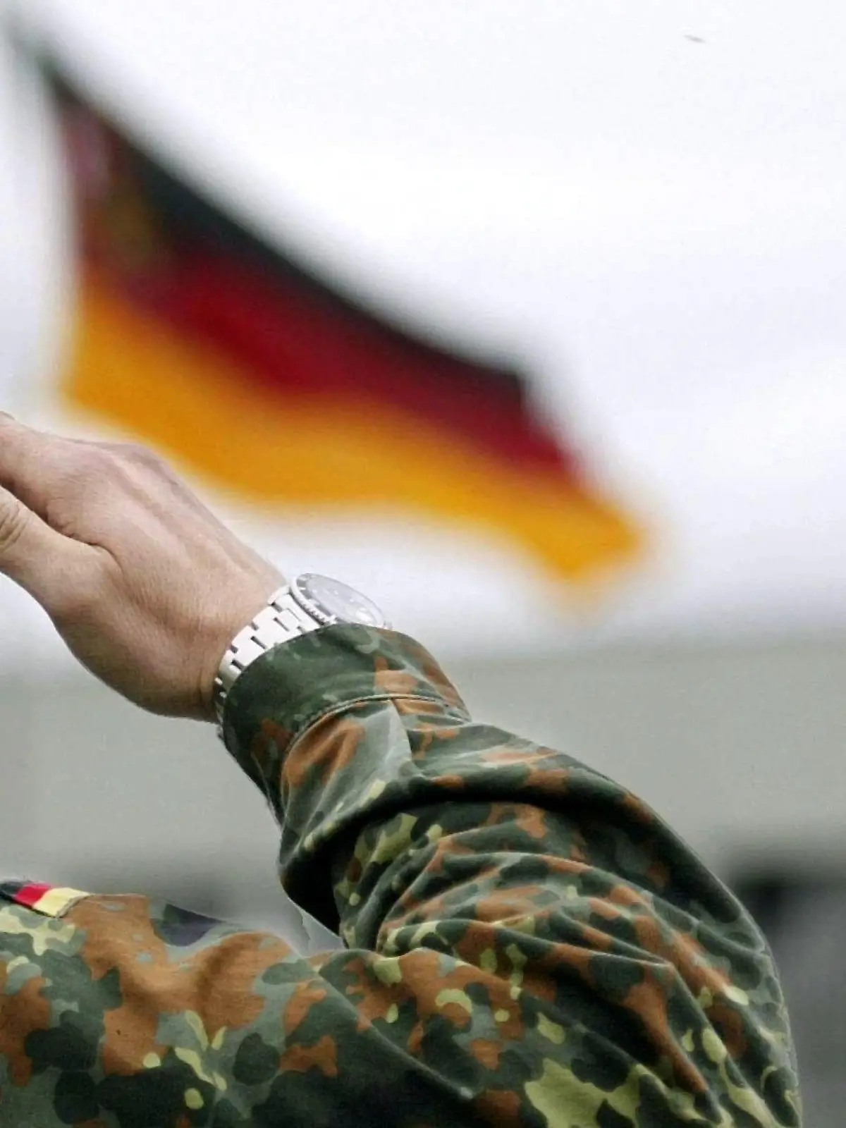 Ein Soldat der Bundeswehr salutiert, während vor ihm die deutsche Fahne weht (aufgenommen am 23.4.2004 in Speyer). Verteidigungsminister Struck (SPD) will gegen das Kölner Gerichtsurteil zur Einberufungspraxis der Bundeswehr Rechtsmittel einlegen. "Ich bin nach wie vor der Überzeugung, dass unser Rechtsstandpunkt sich vor dem Bundesverwaltungsgericht durchsetzen wird", sagte Struck am 23. April 2004. Das Verwaltungsgericht hatte entschieden, dass die derzeitige Einberufungsregelung gegen das Willkürverbot des Grundgesetzes verstößt. Er empfinde die jetzige Situation bei der Einberufung "nicht als ungerecht", so Struck. Von den Männern eines Jahrgangs blieben für den Wehrdienst nur etwa 35 Prozent übrig, weil der Rest verweigere oder aus gesundheitlichen Gründen nicht eingezogen werden könne. Zur Regelung, dass keine Verheirateten und keine Männer über 23 Jahren mehr eingezogen werden, sei ein Gesetzentwurf in Arbeit.