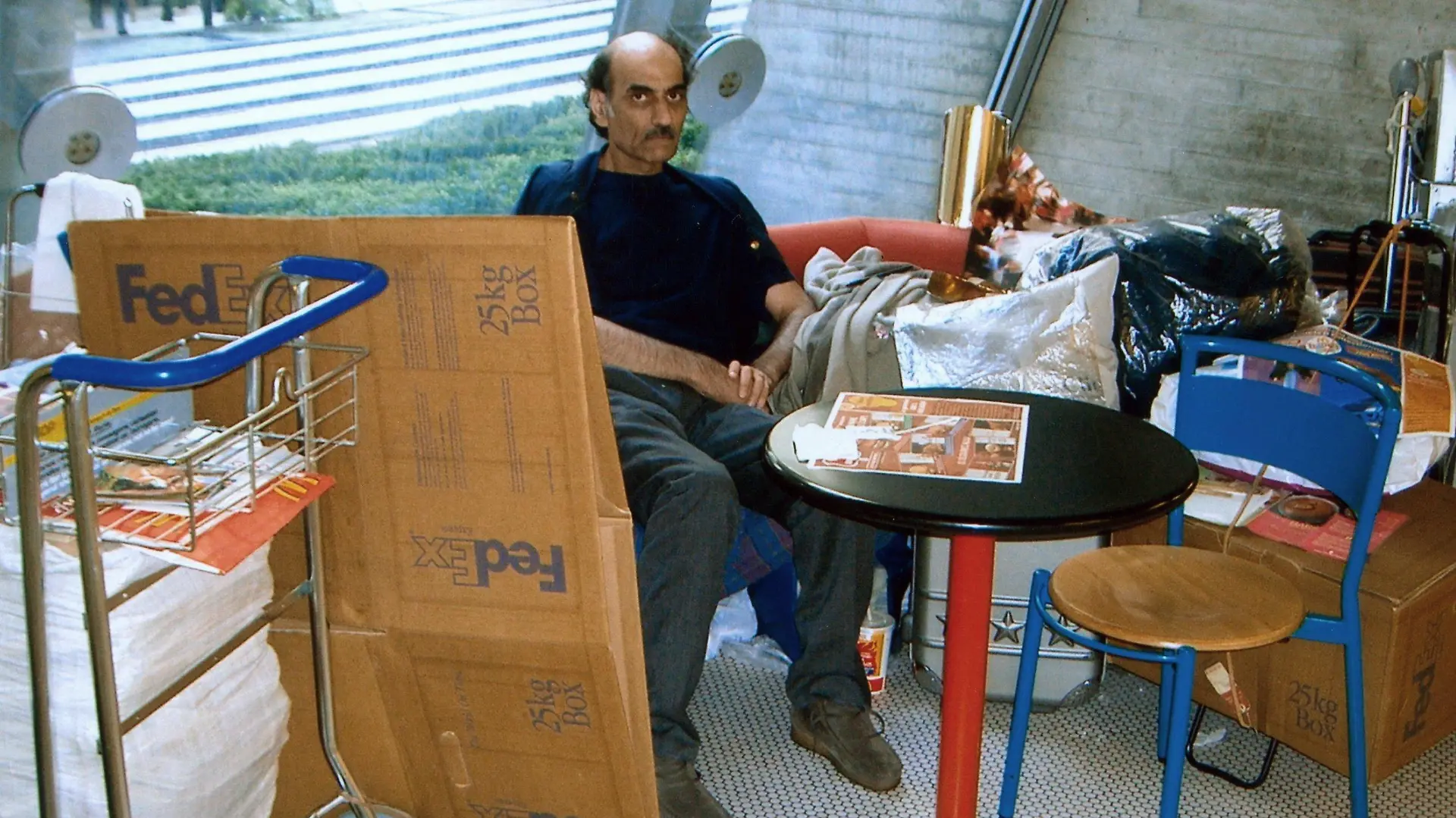 Merhan Karimi Nassiri lebt seit 16 Jahren auf dem Pariser Flughafen Charles de Gaulle (Foto vom 04.09.2004). Seitdem wartet er hier auf seinen Pass, um dann nach Kanada auswandern zu können, erzählt er. Eine halbkreisförmige rote Bank ist seine Wohnstatt. Alle Beschäftigten des Flughafens kennen und respektieren ihn, seine Anwesenheit wird toleriert. Die Lebensgeschichte Nassiris ist so skurril, dass sich US-Regisseur Spielberg die Rechte an der Story sicherte. Im Oktober soll sein Film "Terminal" mit Tom Hanks in der Hauptrolle in die deutschen Kinos kommen. Foto: Stephan Isernhagen dpa