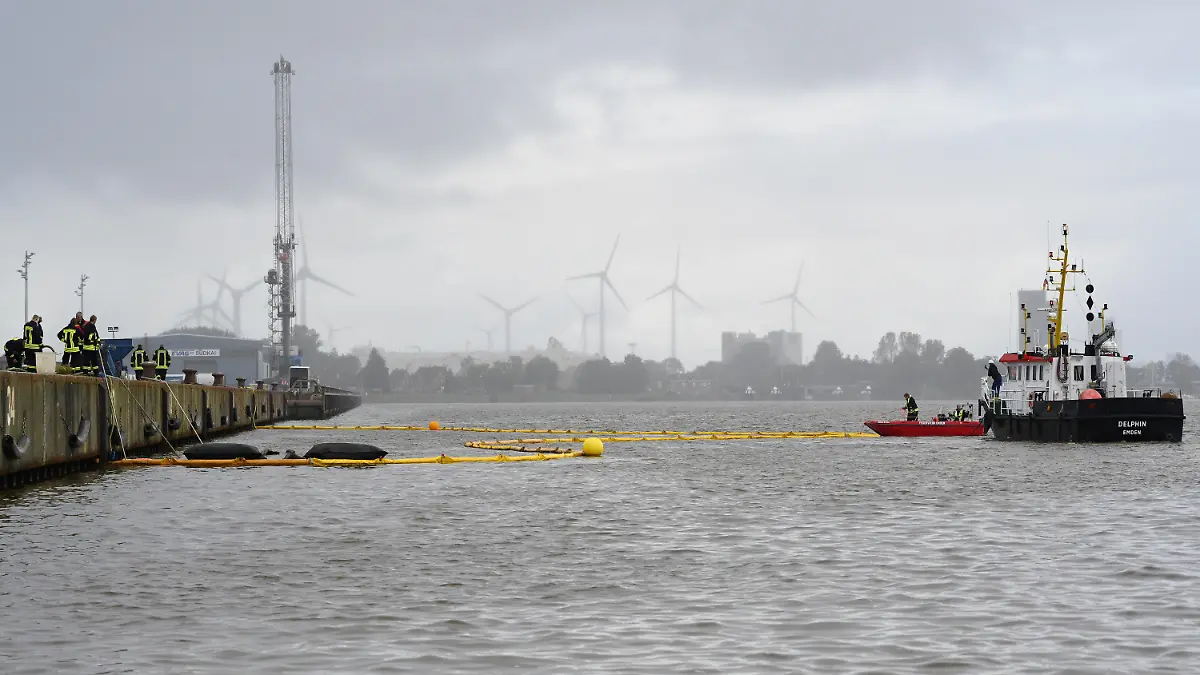 05.10.2023, Niedersachsen, Emden: Die Feuerwehr bringt mit Hilfe von zwei Schiffen Ölsperren im Hafen aus. Ein Binnenschiff ist im Emder Hafen in Niedersachsen aus zunächst unklarer Ursache beim Beladen am Südkai auseinandergebrochen und auf den Grund gesunken. Foto: Lars Penning/dpa +++ dpa-Bildfunk +++