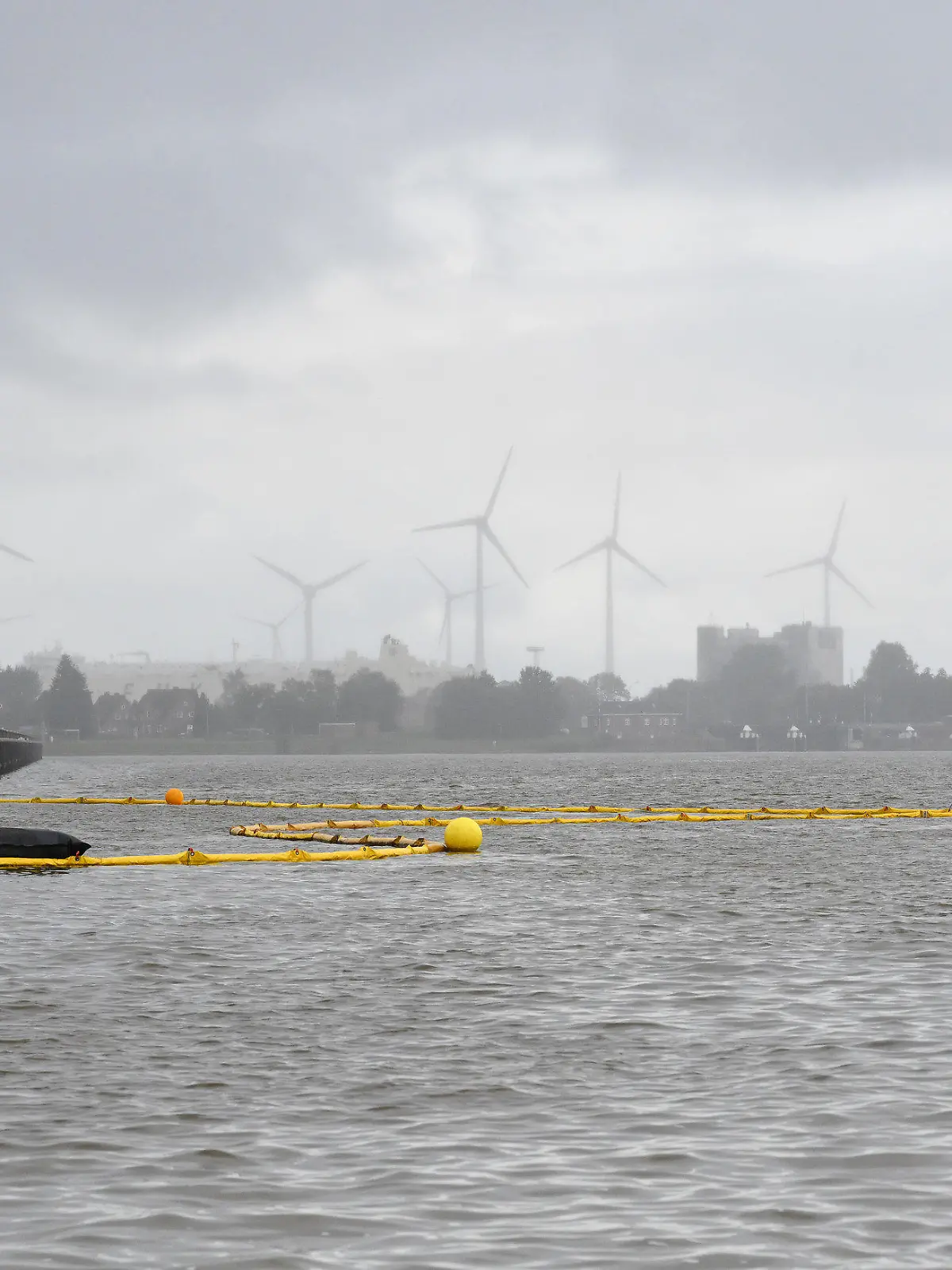 05.10.2023, Niedersachsen, Emden: Die Feuerwehr bringt mit Hilfe von zwei Schiffen Ölsperren im Hafen aus. Ein Binnenschiff ist im Emder Hafen in Niedersachsen aus zunächst unklarer Ursache beim Beladen am Südkai auseinandergebrochen und auf den Grund gesunken. Foto: Lars Penning/dpa +++ dpa-Bildfunk +++