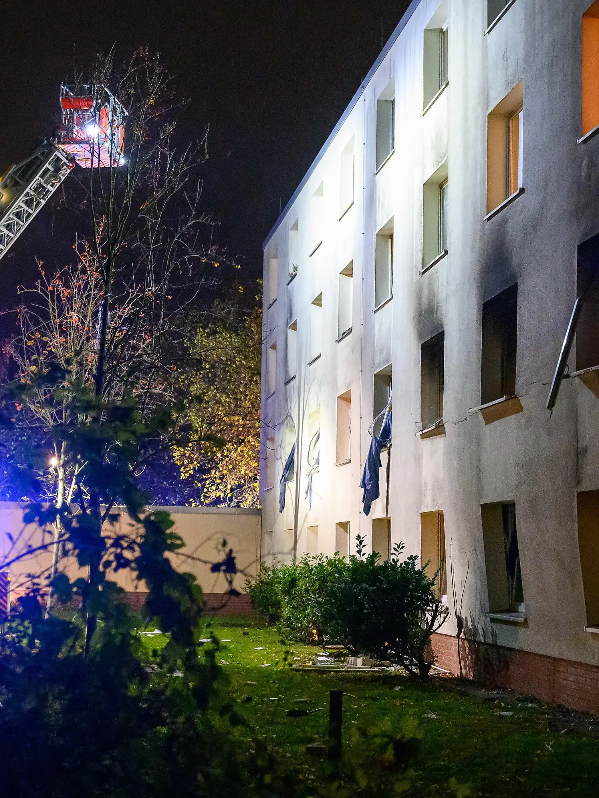 10.11.2022, Hamburg: Eine Drehleiter der Feuerwehr beleuchtet die verrußte und beschädigte Fassade des Gebäudes. Bei einer Explosion in einem Männerwohnheim für Bedürftige in Hamburg-Stellingen ist ein Mann am Donnerstagabend lebensgefährlich verletzt worden. Foto: Jonas Walzberg/dpa +++ dpa-Bildfunk +++