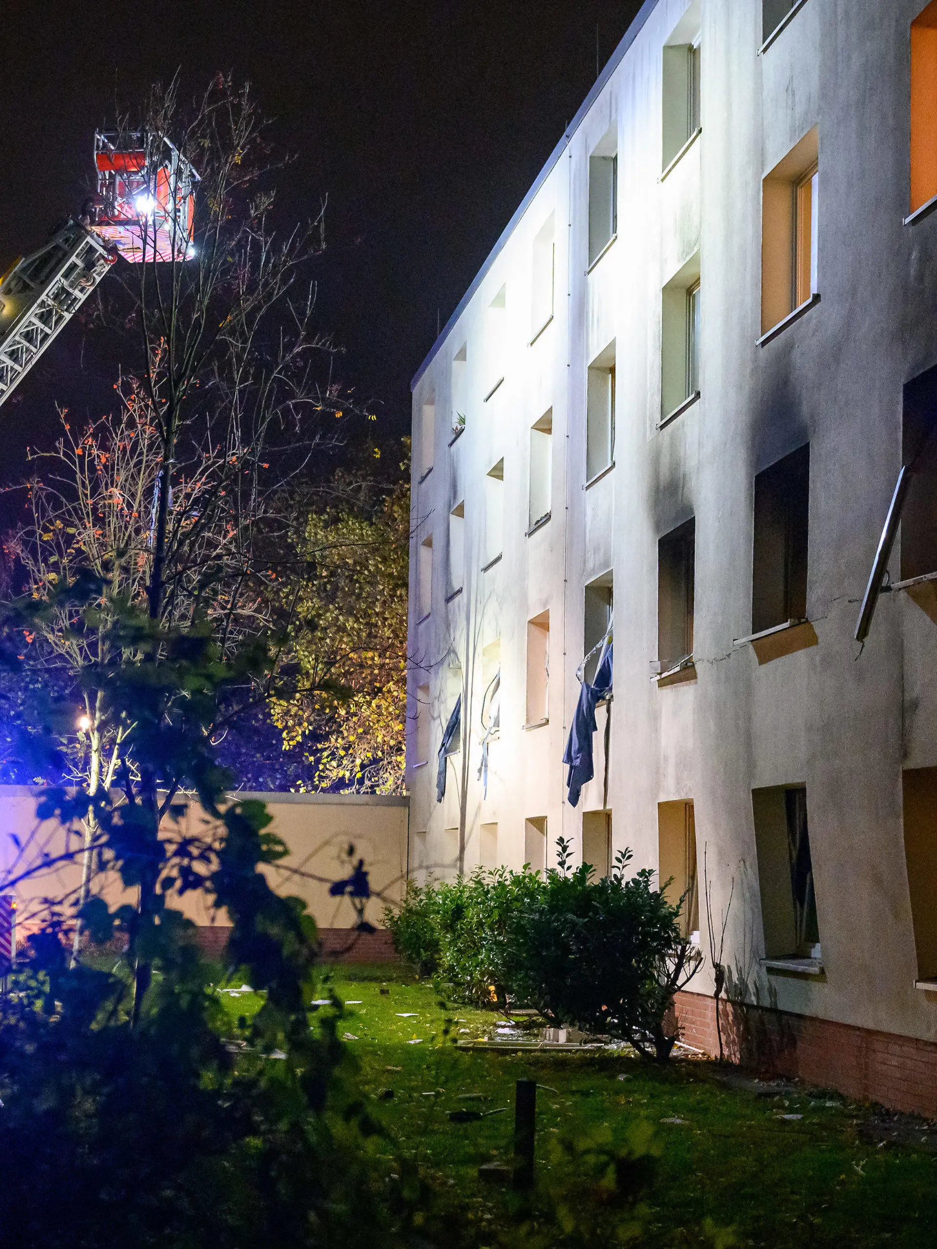 10.11.2022, Hamburg: Eine Drehleiter der Feuerwehr beleuchtet die verrußte und beschädigte Fassade des Gebäudes. Bei einer Explosion in einem Männerwohnheim für Bedürftige in Hamburg-Stellingen ist ein Mann am Donnerstagabend lebensgefährlich verletzt worden. Foto: Jonas Walzberg/dpa +++ dpa-Bildfunk +++