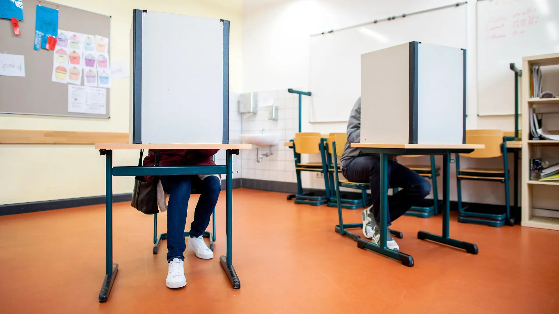 Wähler sitzen in einem Wahlraum in der Lutherschule hinter einem Sichtschutz. Niedersachsen wählt am 09.10.2022 einen neuen Landtag.