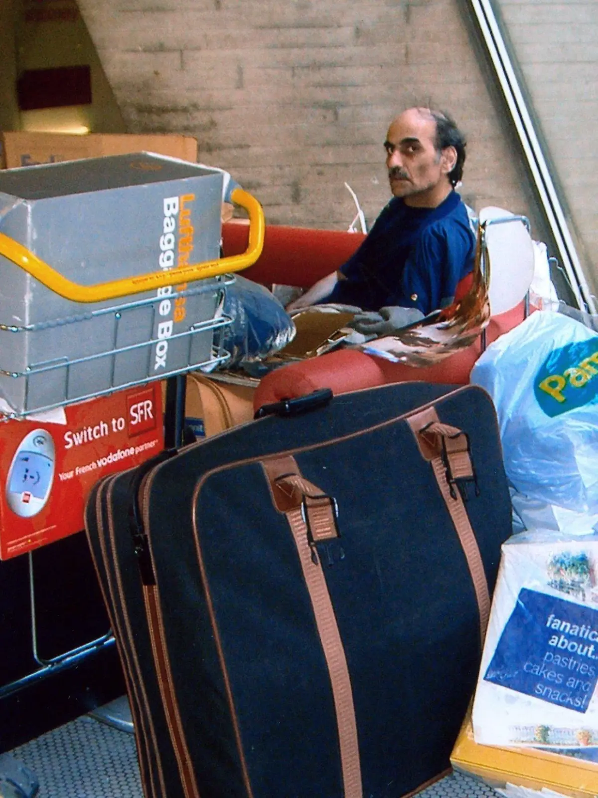 Merhan Karimi Nassiri lebt seit 16 Jahren auf dem Pariser Flughafen Charles de Gaulle (Foto vom 04.09.2004). Seitdem wartet er hier auf seinen Pass, um dann nach Kanada auswandern zu können, erzählt er. Eine halbkreisförmige rote Bank ist seine Wohnstatt. Alle Beschäftigten des Flughafens kennen und respektieren ihn, seine Anwesenheit wird toleriert. Die Lebensgeschichte Nassiris ist so skurril, dass sich US-Regisseur Spielberg die Rechte an der Story sicherte. Im Oktober soll sein Film "Terminal" mit Tom Hanks in der Hauptrolle in die deutschen Kinos kommen. Foto: Stephan Isernhagen dpa
