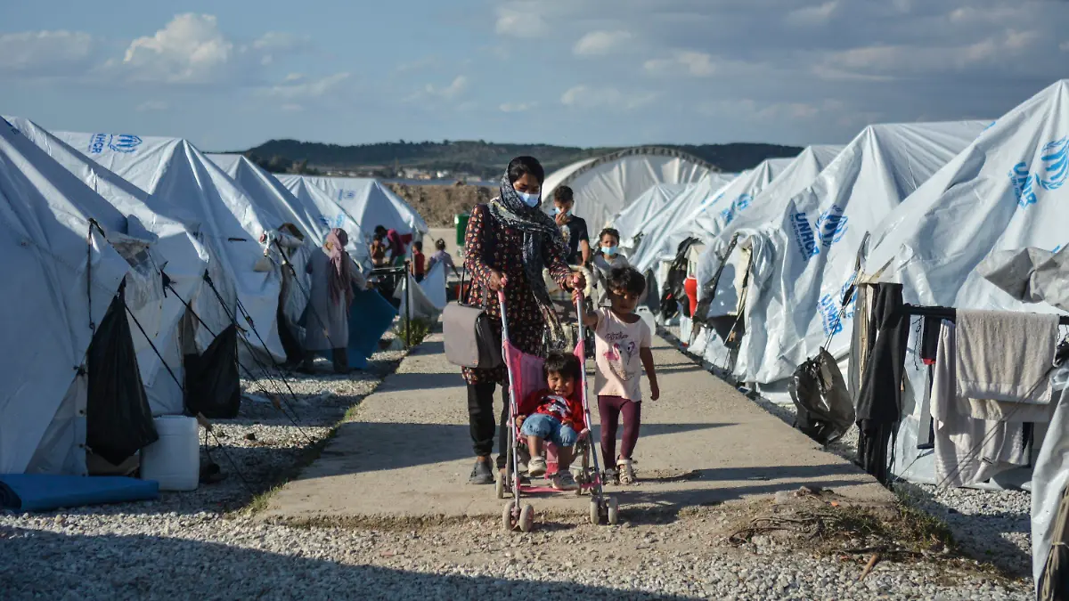 ARCHIV - 14.10.2020, Griechenland, Lesbos: Migranten gehen nach einem starken Regenfällen durch das Flüchtlingslager «Kara Tepe». (zu dpa "Spiegel: Deutschland soll bis zu 5000 Flüchtlinge mehr aufnehmen") Foto: Panagiotis Balaskas/AP/dpa +++ dpa-Bildfunk +++