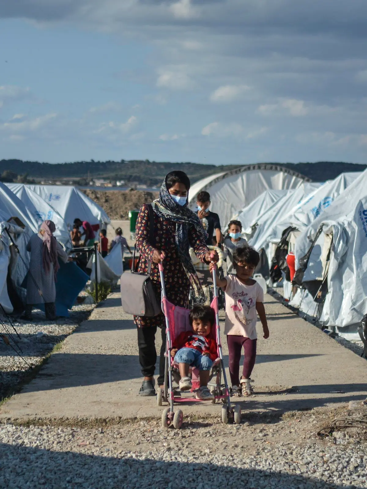 ARCHIV - 14.10.2020, Griechenland, Lesbos: Migranten gehen nach einem starken Regenfällen durch das Flüchtlingslager «Kara Tepe». (zu dpa "Spiegel: Deutschland soll bis zu 5000 Flüchtlinge mehr aufnehmen") Foto: Panagiotis Balaskas/AP/dpa +++ dpa-Bildfunk +++