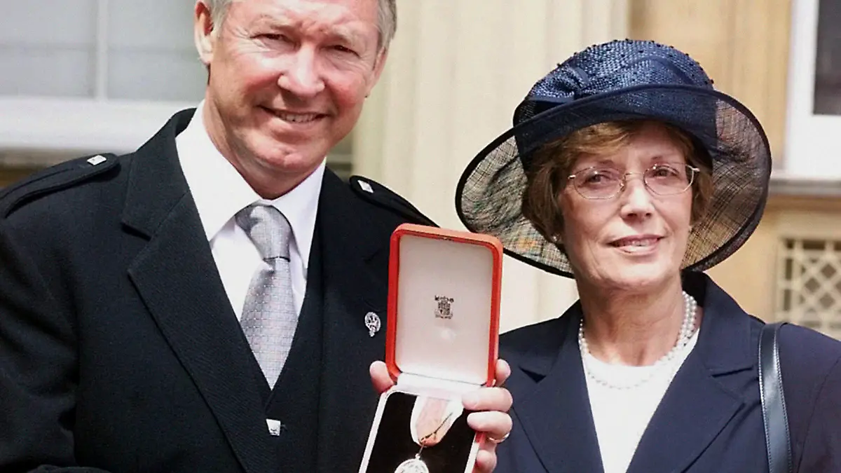 FILE - Manchester United manager Sir Alex Ferguson and wife Cathy after he was knighted by the Queen, in London, July 20 1999. Flags at Old Trafford have been lowered to half-staff following the death of the wife of former Manchester United manager Alex Ferguson. United says in a statement on Friday, Oct. 6, 2023 that Cathy Ferguson has died at the age of 84. (John Stillwell/PA via AP, file)