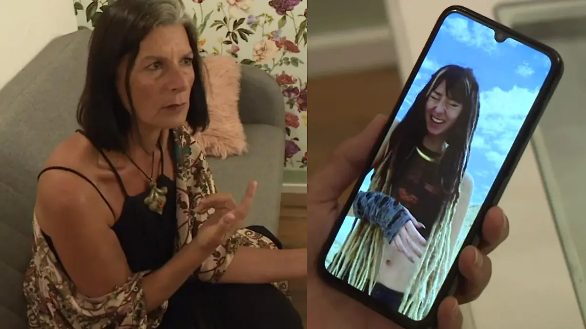 Eine Frau sitzt auf der Couch und hält ein Smartphone in der Hand.