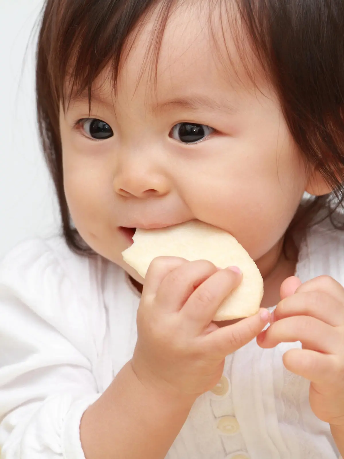 Japanese baby girl eating rice cracker (0 year old)