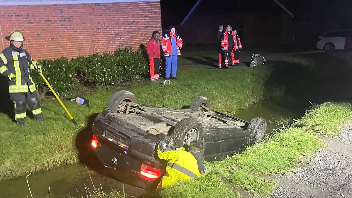 Ein schwarzes Auto liegt auf dem Dach in einem Wassergraben