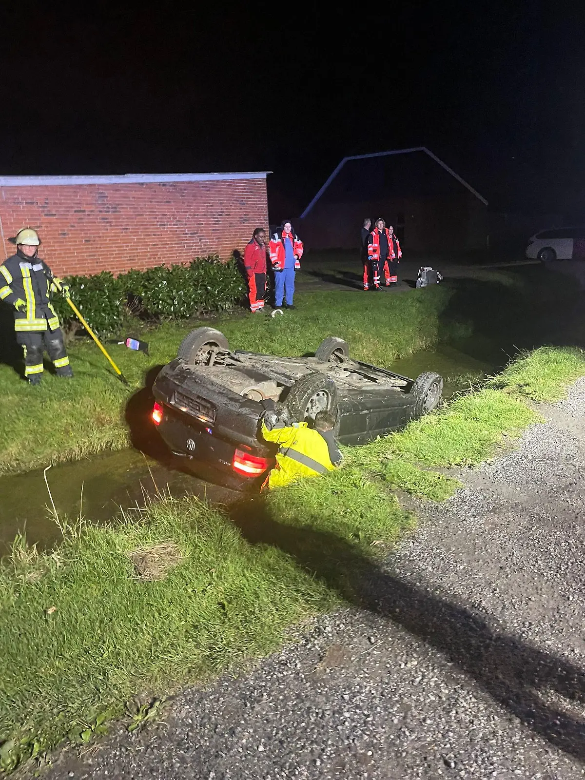 Ein schwarzes Auto liegt auf dem Dach in einem Wassergraben