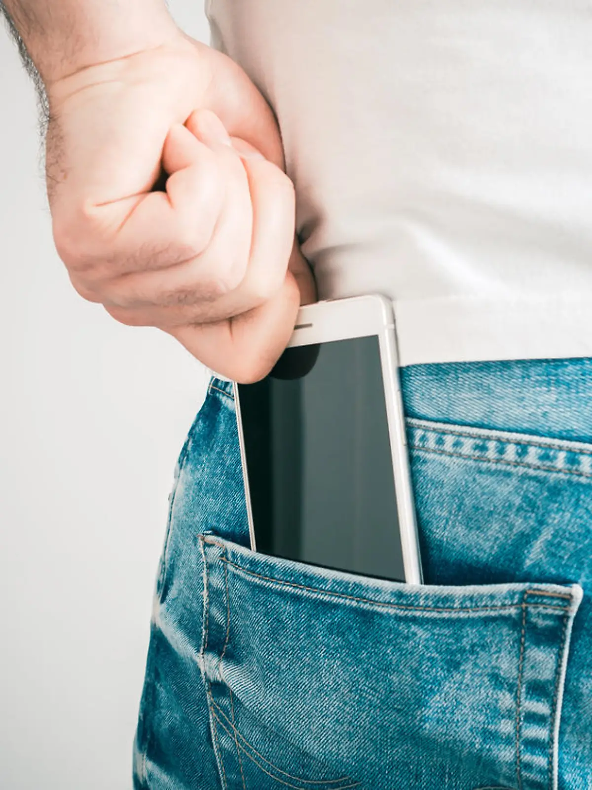 A Male Hand Grabbing A Smartphone In The Left Back Pocket Of A Jeans Trouser