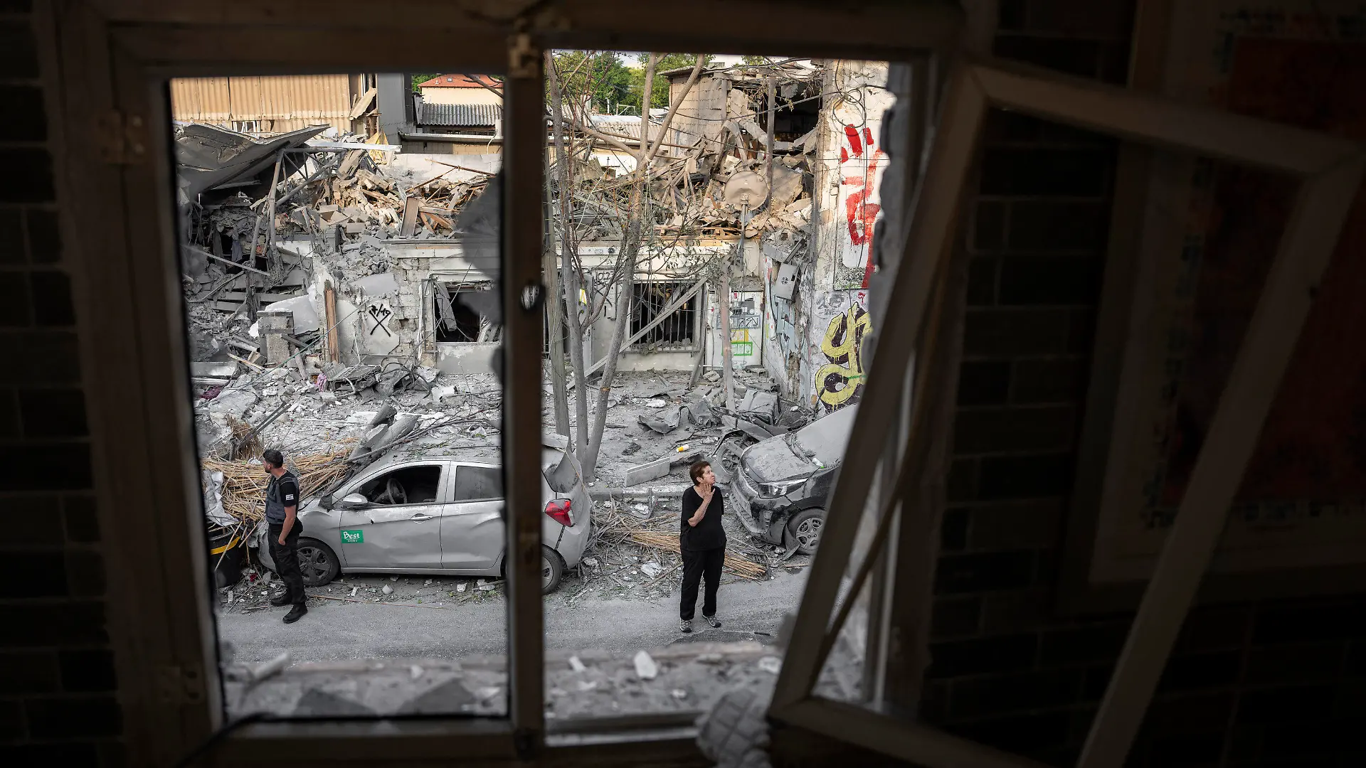 08.10.2023, Israel, Tel Aviv: Israelis inspizieren die Trümmer eines Gebäudes in Tel Aviv, Israel, Sonntag, 8. Oktober 2023, einen Tag nachdem es von einer aus dem Gazastreifen abgefeuerten Rakete getroffen wurde. Israel ist am jüdischen Feiertag Simchat Tora (Freude der Tora) von einer großangelegten Militäraktion der islamistischen Hamas überrascht worden. Hamas griff vom Gazastreifen massiv aus der Luft, am Boden und von See aus an. Beim Gegenangriff des israelischen Militärs auf den Gazastreifen wurden nach palästinensischen Angaben auch dort Hunderte getötet und verletzt. Foto: Oded Balilty/AP/dpa +++ dpa-Bildfunk +++