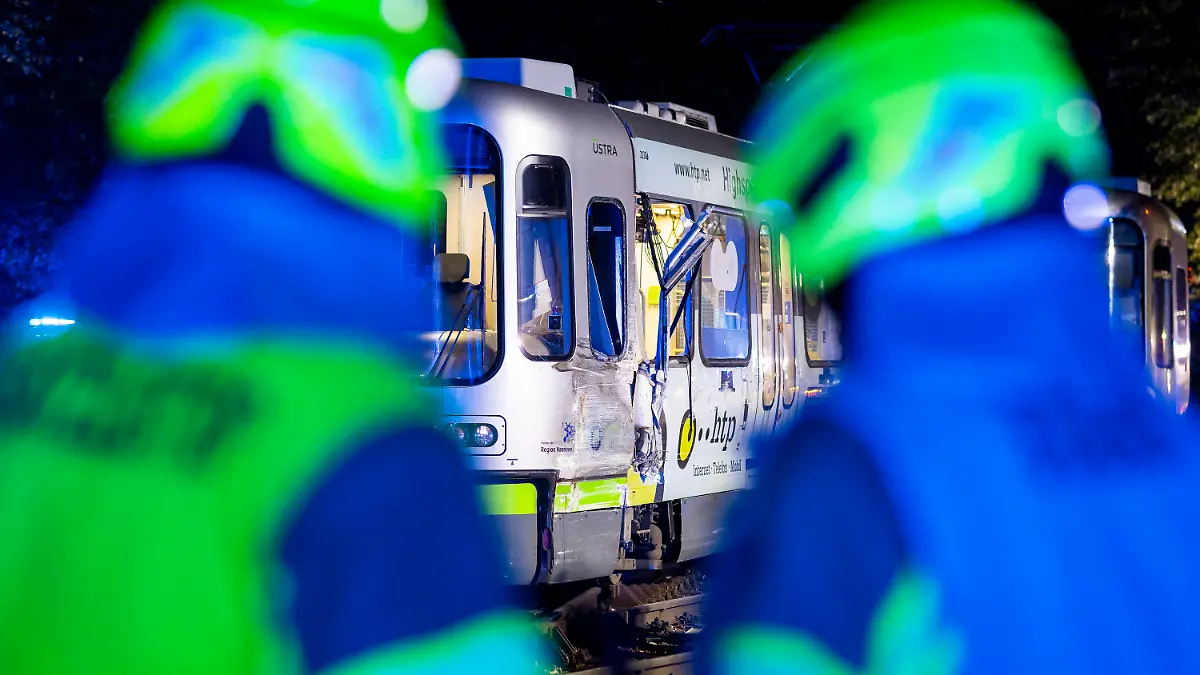 10.10.2023, Niedersachsen, Hannover: Zwei Einsatzkräfte der Feuerwehr stehen vor einer Straßenbahn, nachdem zwei Straßenbahnen kollidiert sind. Mindestens 20 Menschen wurden verletzt. Foto: Moritz Frankenberg/dpa +++ dpa-Bildfunk +++