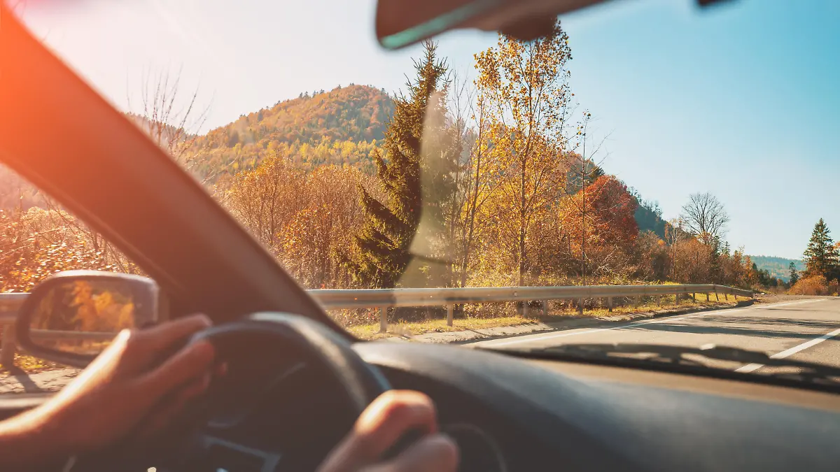 Driving a car on mountain road. Empty road on a sunny day. View from car of mountain landscape in autumn