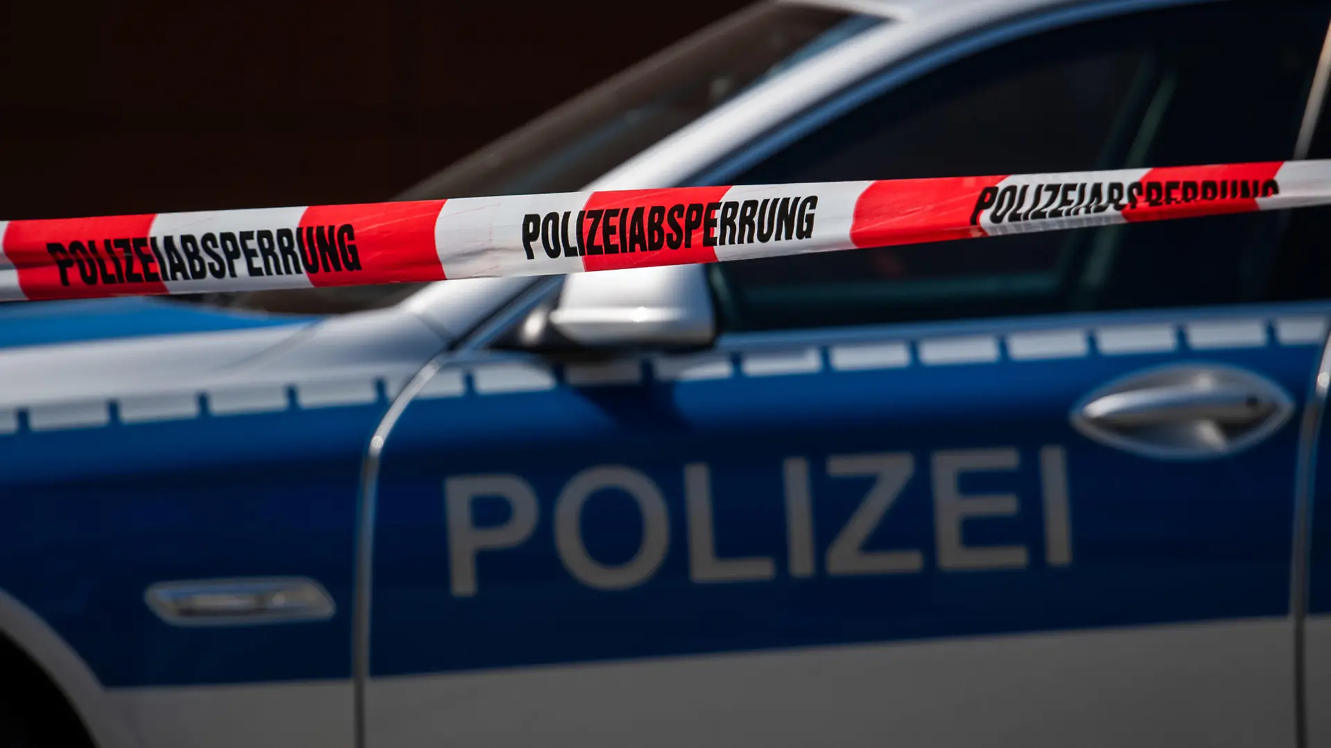 ARCHIV - 07.04.2020, Sachsen, Görlitz: Ein Polizeiauto steht hinter einem Absperrband der Polizei. (Zu dpa: «Rund 250 scharfe Waffen bei mutmaßlich rechten Aktivisten entdeckt»). Foto: Robert Michael/dpa-Zentralbild/dpa +++ dpa-Bildfunk +++