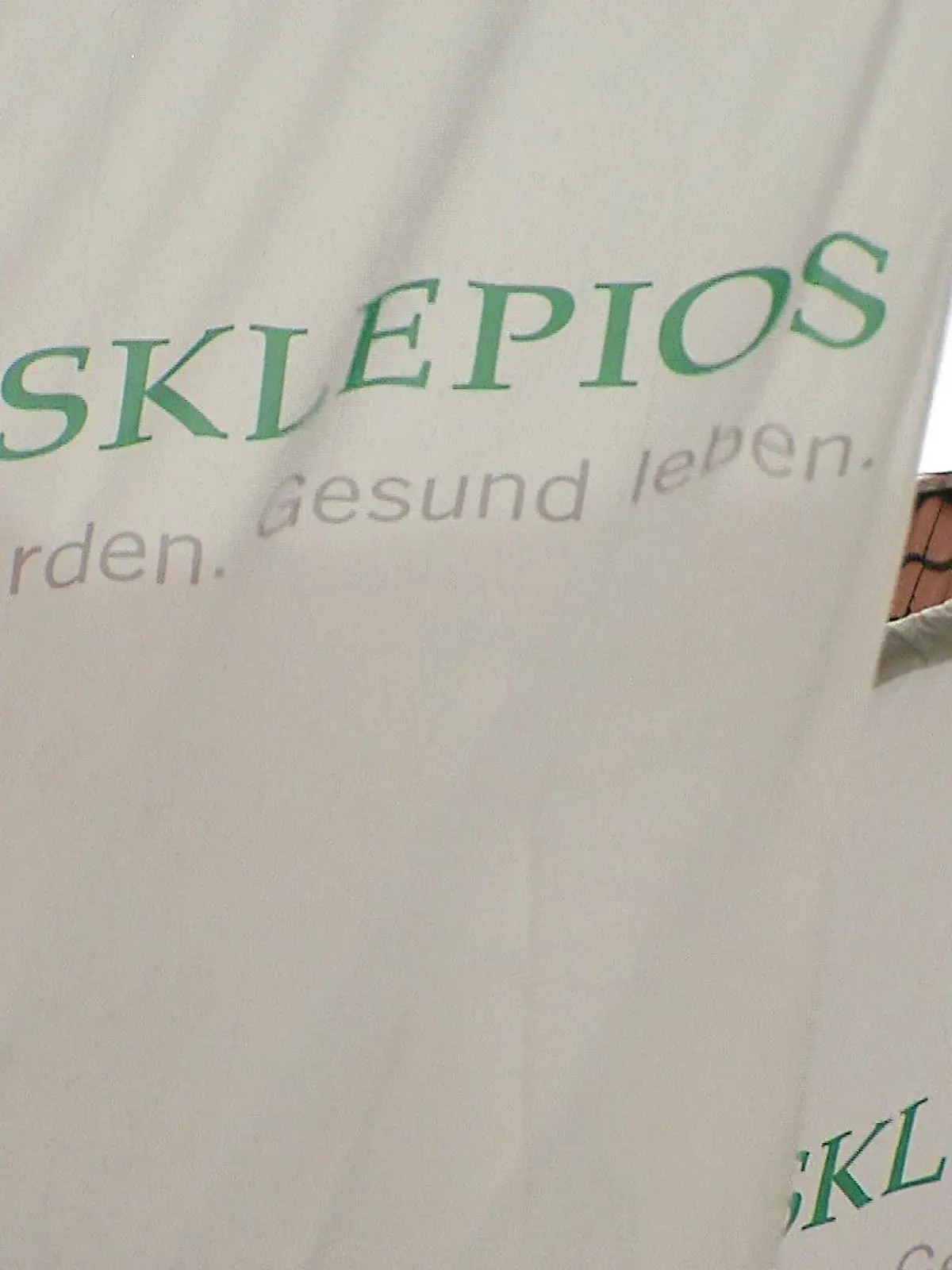 Mehrere Fahnen, auf denen das Logo der Asklepios-Kliniken-Gruppe zu sehen ist.