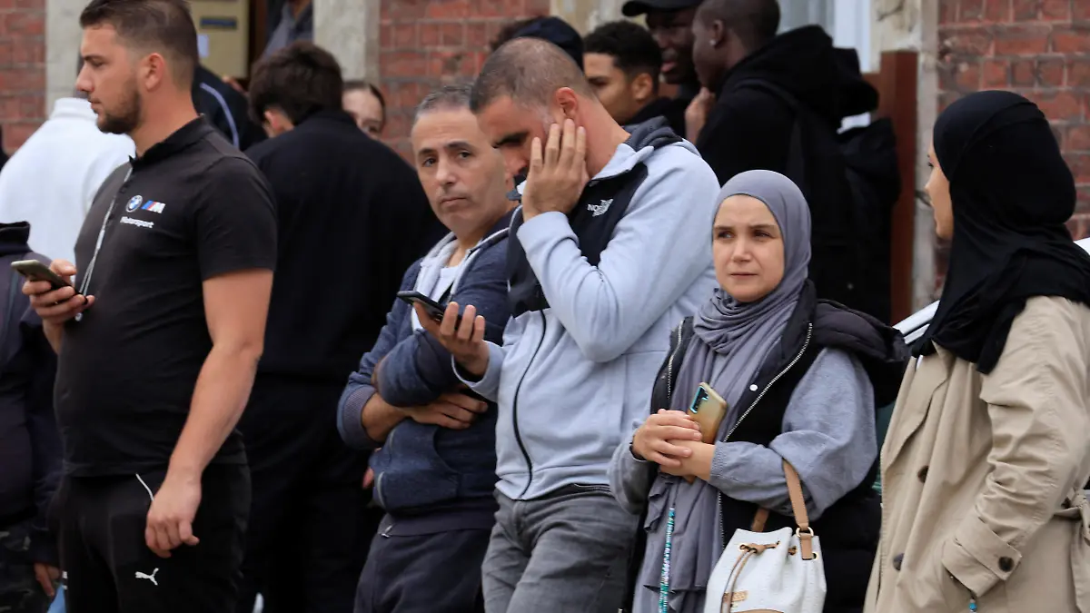 People stand near the Lycee Gambetta-Carnot high school after a teacher was killed and several people injured in a knife attack in Arras, northern France, October 13, 2023. REUTERS/Pascal Rossignol