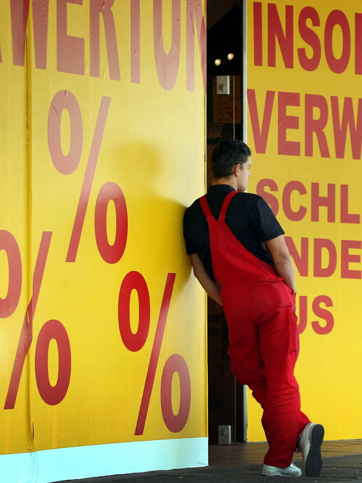 ARCHIV - 26.05.2009, Nordrhein-Westfalen, Düsseldorf: Ein Mann lehnt am Hinweisschild einer Insolvenzverwertung. Die Zahl der Unternehmens- und Verbraucher-Insolvenzen hat in Nordrhein-Westfalen zugenommen. (zu dpa «Mehr Insolvenzen in NRW») Foto: Martin Gerten/dpa +++ dpa-Bildfunk +++