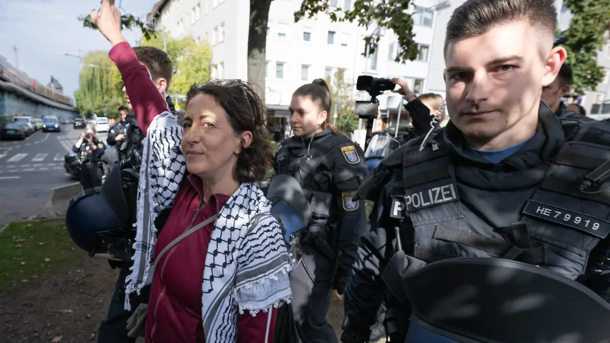 13.10.2023, Hessen, Frankfurt/Main: Die palästinensische Aktivistin Aitak Barani (2.v.l) wird nach ihrer Festnahme von Polizisten abgeführt. Nach bisheriger Darstellung der Polizei hatte sie sich zuvor bei einer improvisierten Pressekonferenz volksverhetzend geäußert. Foto: Boris Roessler/dpa +++ dpa-Bildfunk +++