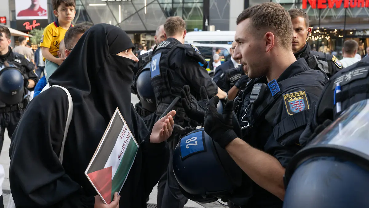 11.10.2023, Hessen, Frankfurt/Main: Ein Frau kommt mit einem Schild mit der Aufschrift "Free Palestine" zu einer spontanen pro-palästinensischen Kundgebung in Frankfurt und diskutiert mit einem Polizisten. Foto: Boris Roessler/dpa +++ dpa-Bildfunk +++