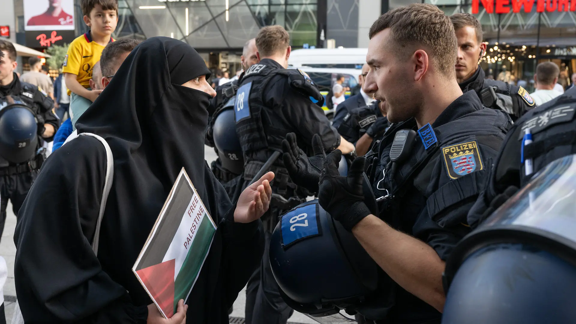 11.10.2023, Hessen, Frankfurt/Main: Ein Frau kommt mit einem Schild mit der Aufschrift "Free Palestine" zu einer spontanen pro-palästinensischen Kundgebung in Frankfurt und diskutiert mit einem Polizisten. Foto: Boris Roessler/dpa +++ dpa-Bildfunk +++