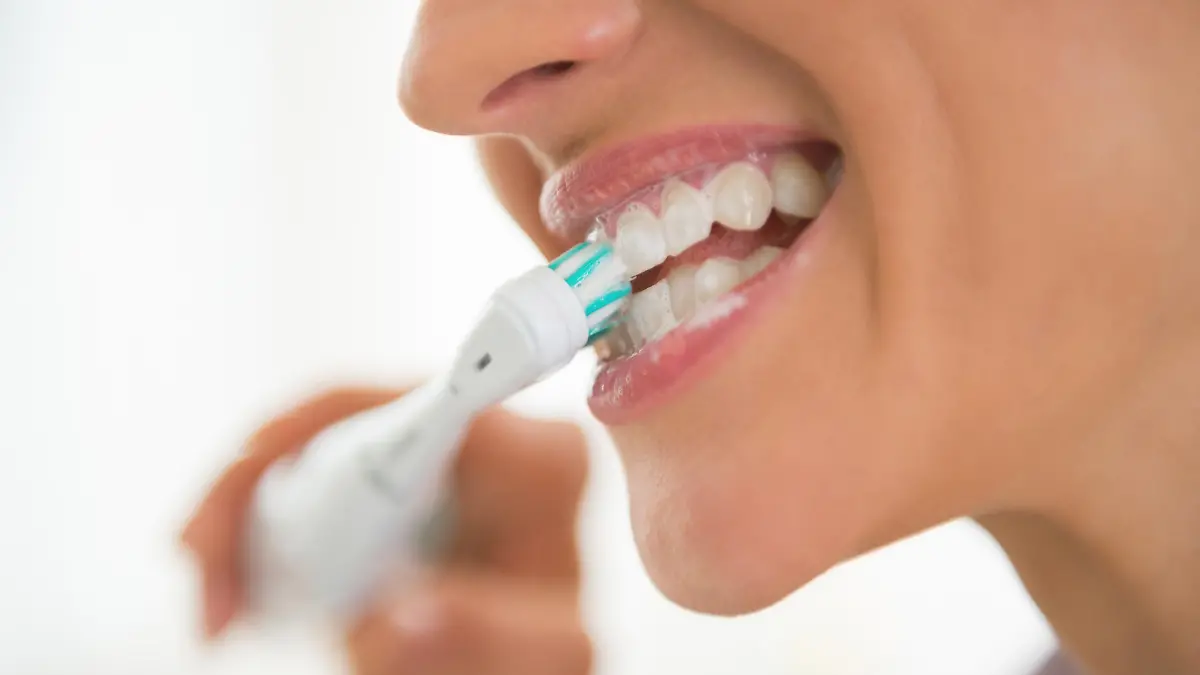 Closeup on young woman brushing teeth