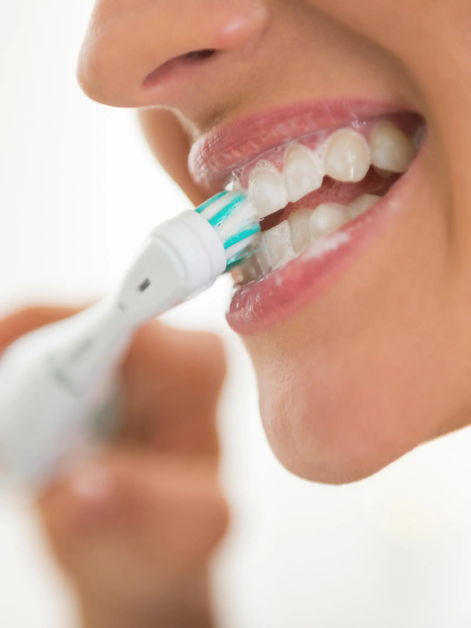 Closeup on young woman brushing teeth