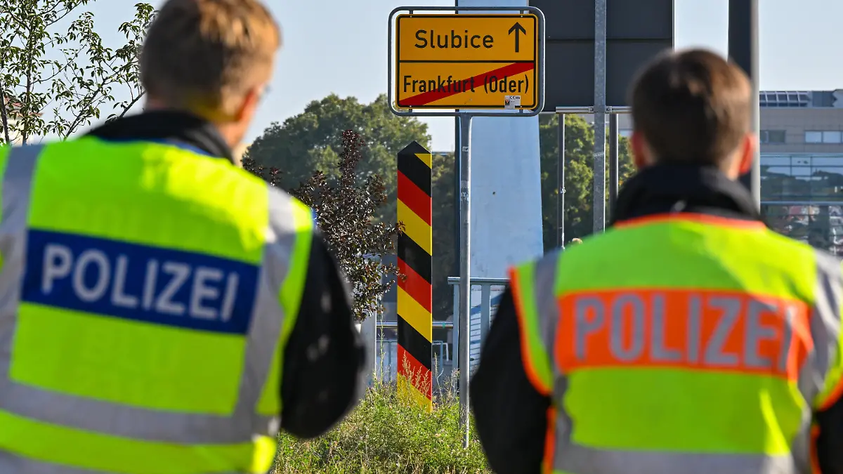 28.09.2023, Brandenburg, Frankfurt (Oder): Zwei Beamte der Bundespolizei stehen am deutsch-polnischen Grenzübergang Stadtbrücke bei einer Kontrolle gegen die Schleuserkriminalität. Derzeit werden in dieser Grenzregion zu Polen mehrfach am Tag Migranten aufgegriffen. Foto: Patrick Pleul/dpa +++ dpa-Bildfunk +++