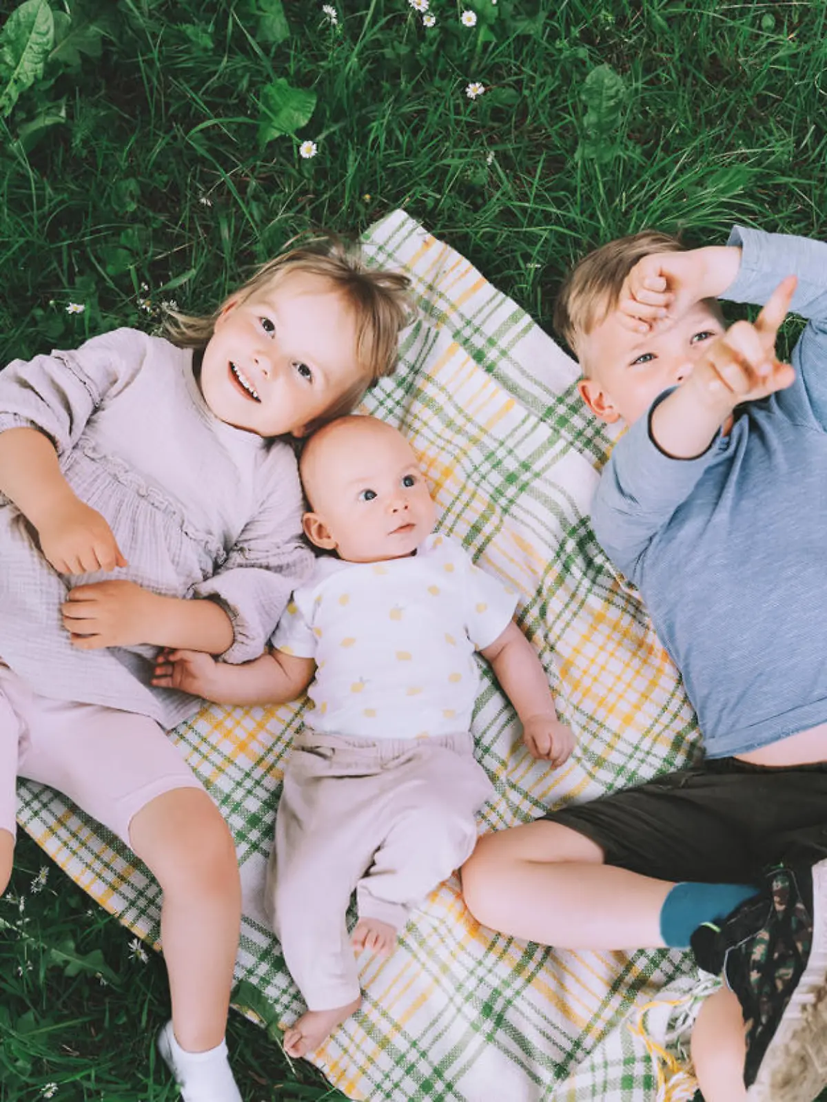 Children in nature. Preschool small kids play on green grass outdoors in summer. Siblings friendship. Holidays with family. Happy and healthy lifestyle. Minimalist style photo.