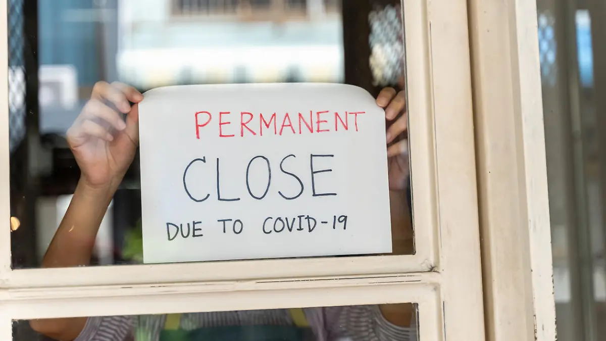 Young Asian woman small business owner attaching permanent close sign on the store window, bankrupt business due to financial crisis from coronavirus pandemic.