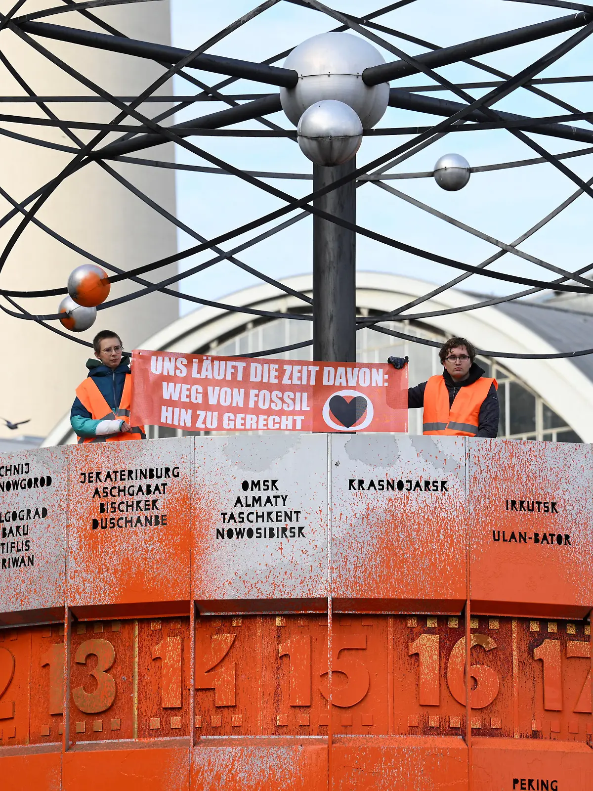 Activists of the 'Letzte Generation' (Last Generation) sit on the World clock (Weltzeituhr) and show a banner with the lettering: "We are running out of time, away from fossil to fair" after the World clock was painted at Alexanderplatz in Berlin, Germany October 17, 2023. REUTERS/Annegret Hilse