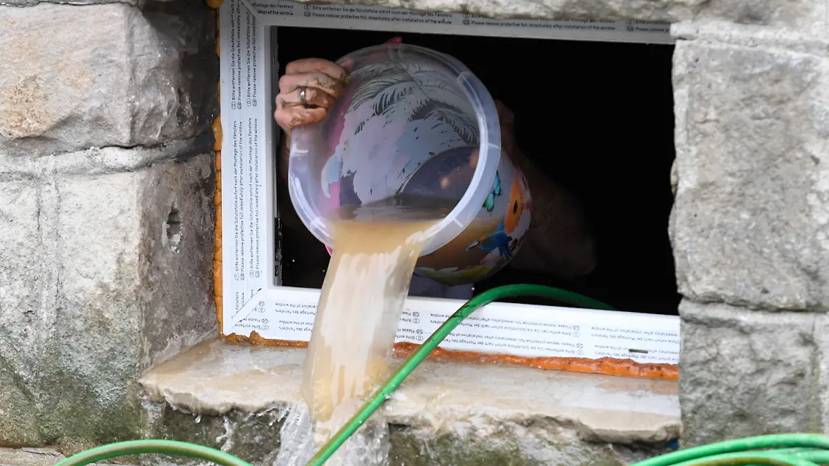 15.07.2021, Nordrhein-Westfalen, Hagen: Ein Anwohner beseitigt seine Schäden im Keller, in dem er kurzerhand das Wasser mit einem Eimer aus dem Keller befördert, die die Überflutung der Nahmer gestern abend mit sich gebracht hat. Durch die heftigen Regenfälle war das Flüsschen zum reissenden Fluss geworden. Foto: Roberto Pfeil/dpa +++ dpa-Bildfunk +++