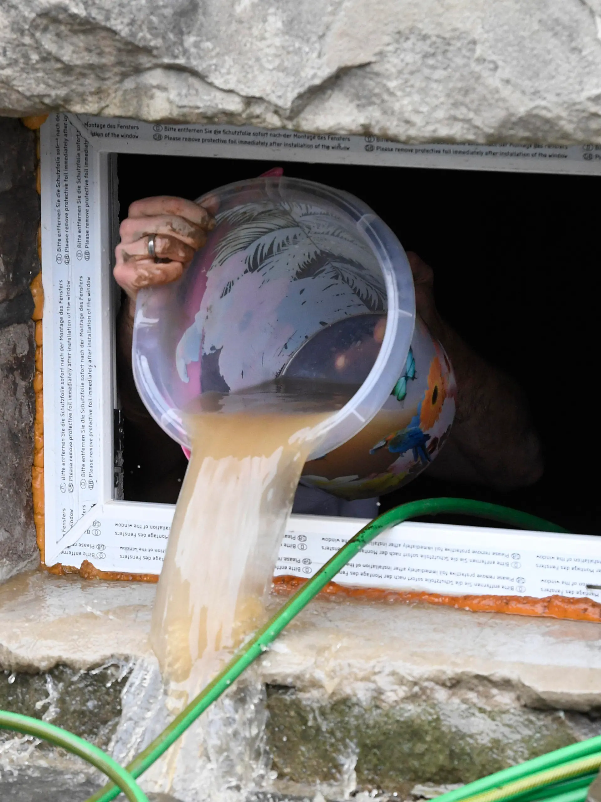 15.07.2021, Nordrhein-Westfalen, Hagen: Ein Anwohner beseitigt seine Schäden im Keller, in dem er kurzerhand das Wasser mit einem Eimer aus dem Keller befördert, die die Überflutung der Nahmer gestern abend mit sich gebracht hat. Durch die heftigen Regenfälle war das Flüsschen zum reissenden Fluss geworden. Foto: Roberto Pfeil/dpa +++ dpa-Bildfunk +++