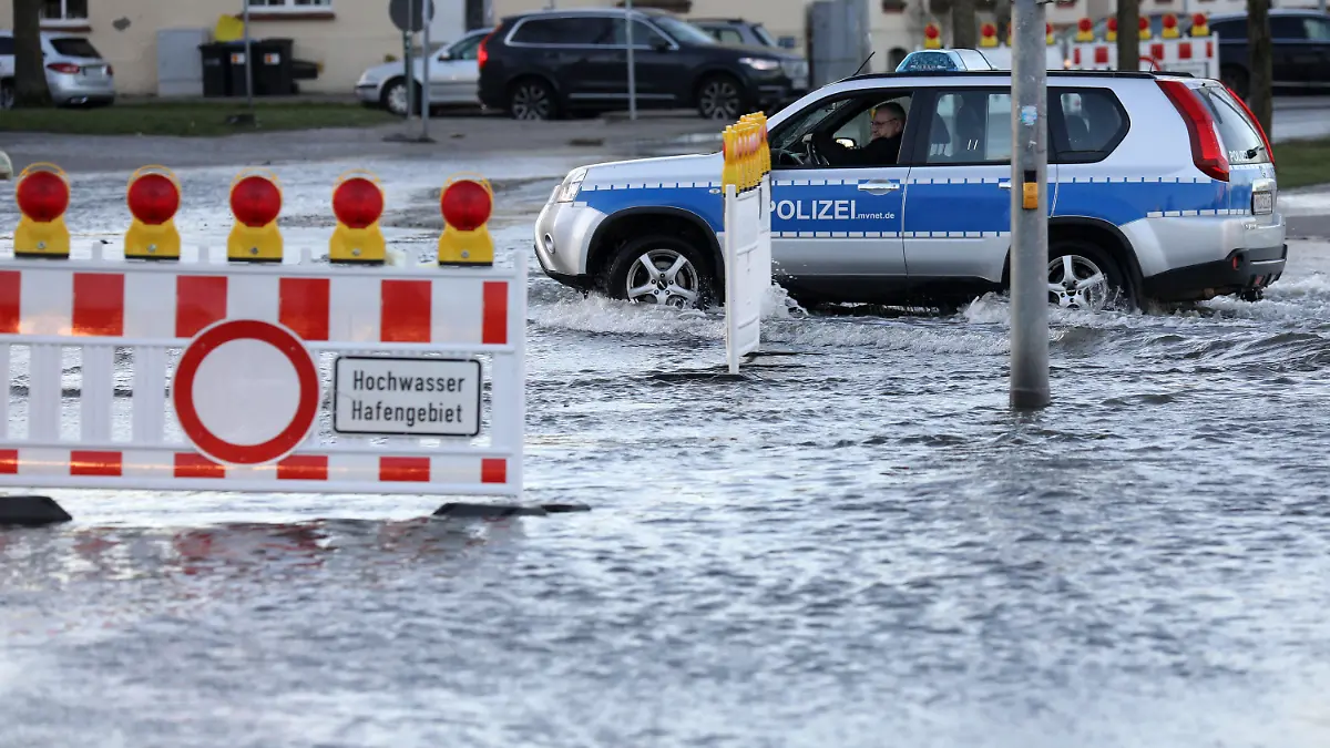 02.01.2019, Mecklenburg-Vorpommern, Wismar: Ein Polizeiauto fährt an Absperrungen vorbei. Nach einer Sturmflut stehen am Hafen Straßen unter Wasser. Foto: Bernd Wüstneck/dpa +++ dpa-Bildfunk +++