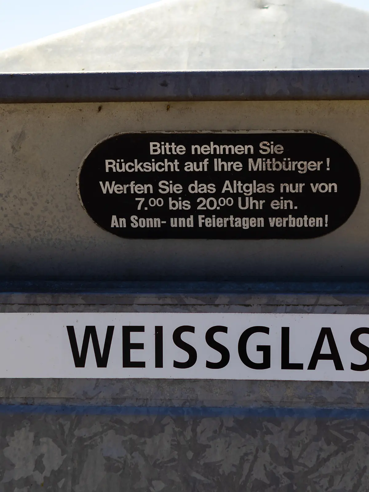 Einwurf eines Altglascontainers mit Hinweis auf die Benutzungszeiten