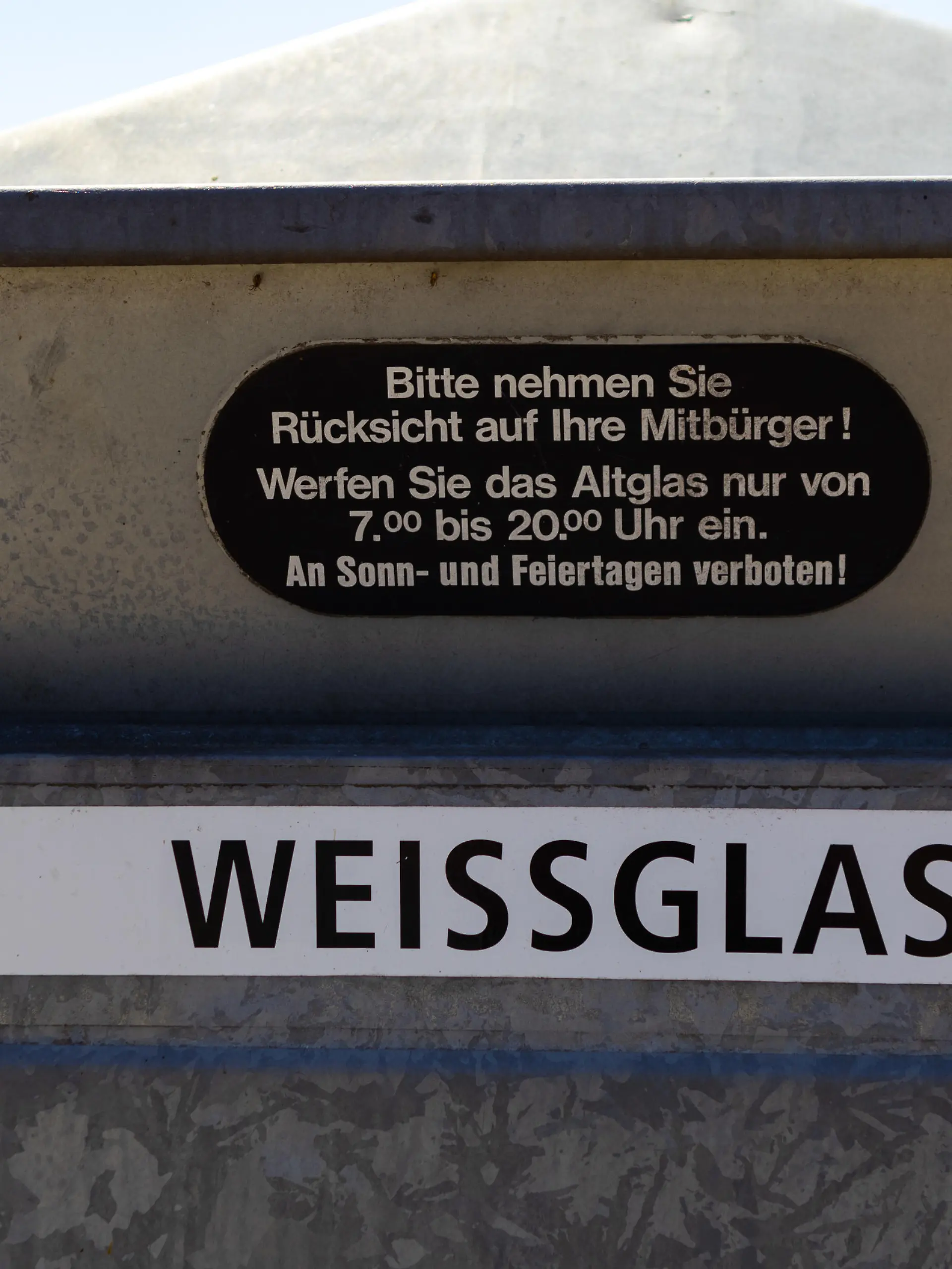 Einwurf eines Altglascontainers mit Hinweis auf die Benutzungszeiten