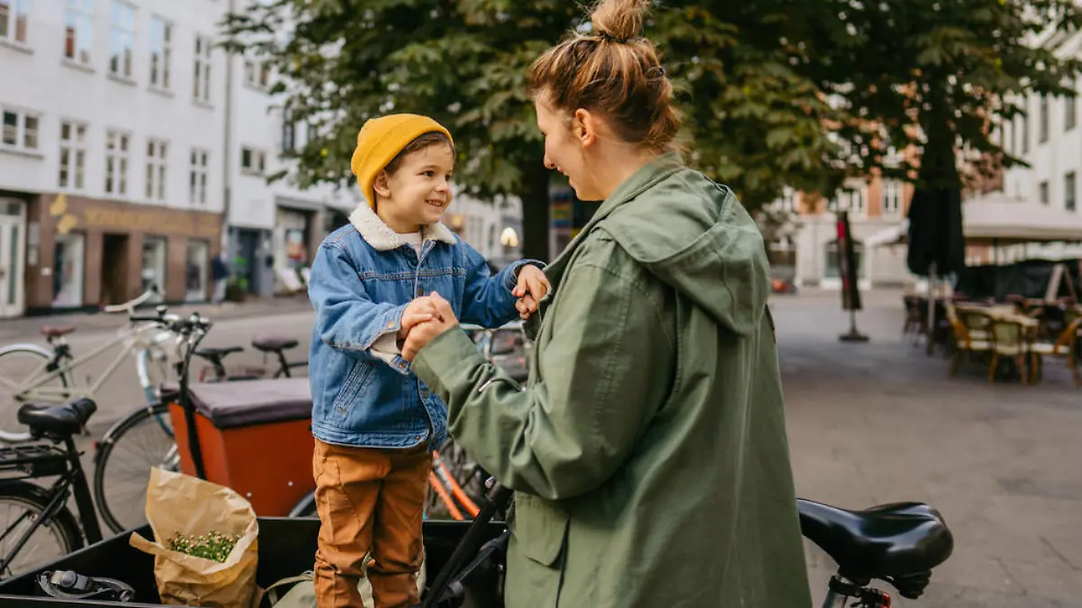 Photo of a mother and her son being playful while riding the cargo bike and running errands around the city.