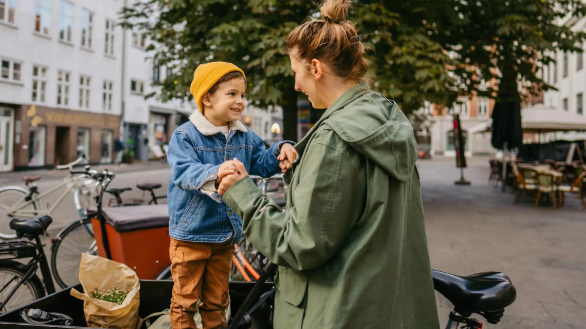 Photo of a mother and her son being playful while riding the cargo bike and running errands around the city.