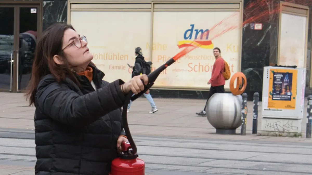 17.10.2023, Berlin: Eine Aktivistin der Gruppe Letzte Generation färbt die Weltzeituhr am Alexanderplatz orange ein. Foto: Paul Zinken/dpa +++ dpa-Bildfunk +++