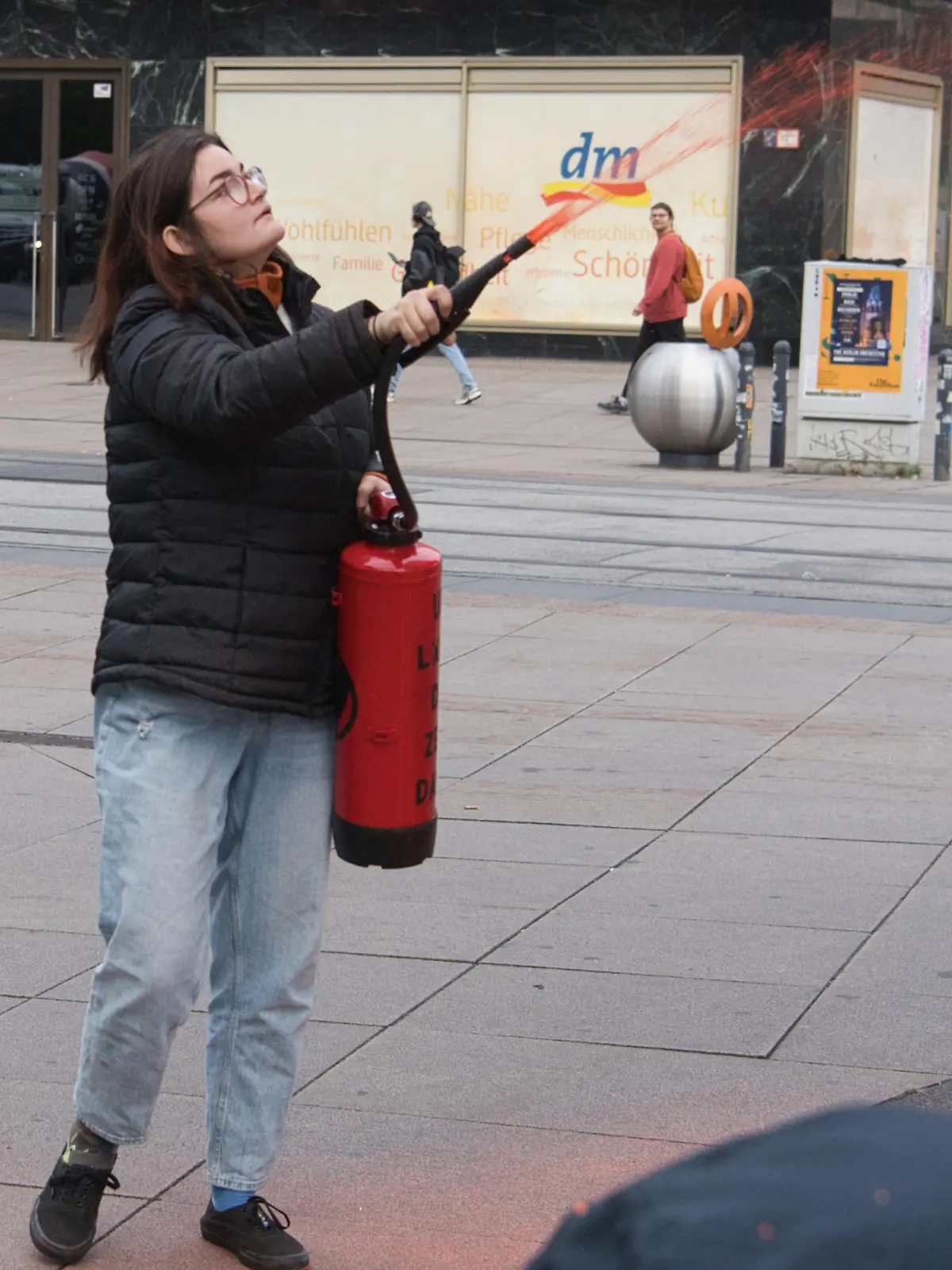 17.10.2023, Berlin: Eine Aktivistin der Gruppe Letzte Generation färbt die Weltzeituhr am Alexanderplatz orange ein. Foto: Paul Zinken/dpa +++ dpa-Bildfunk +++